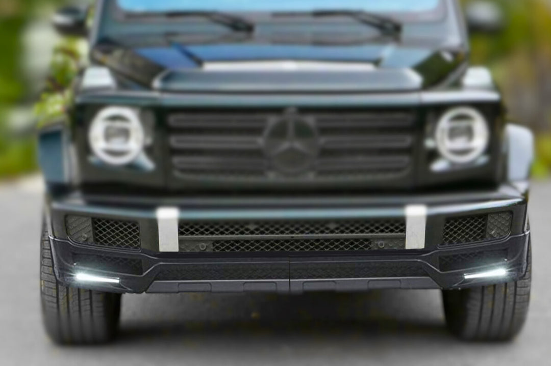 close up focusing on DMC front lip installed on black G-Wagon =, background blurred out so the focal point is the front lip with the led light son