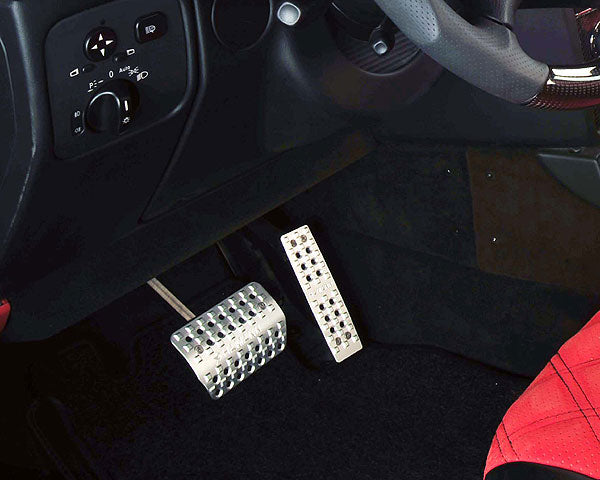 Hamann Motorsport silver anodized aluminum pedals installed in Mercedes-Benz G-Class W463 interior, showcasing premium tread design and reflective finish.