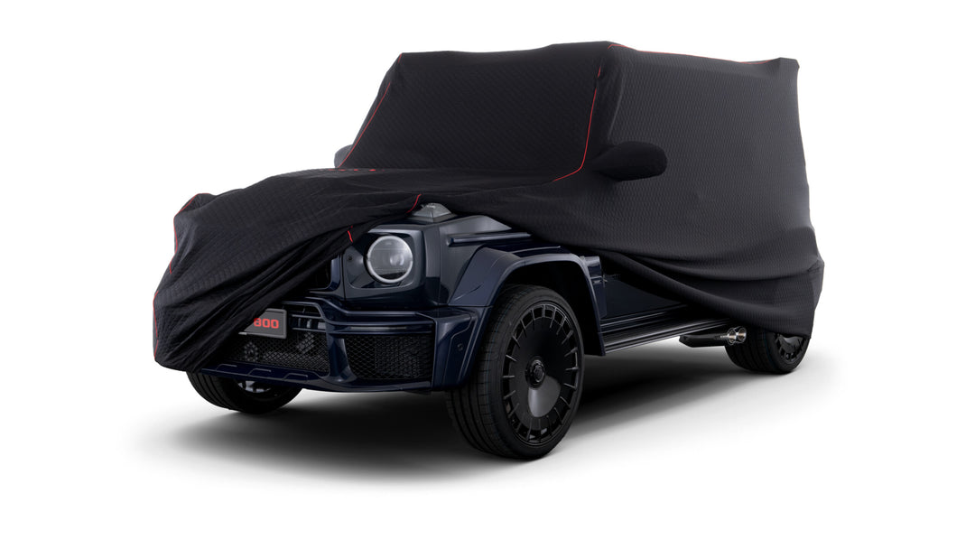 BRABUS G-Class Car Cover - Premium quilted black fabric with red contour liner and embroidered BRABUS logo, tailored for W463A and W465 models front right view with the cover pulled up exposing the front fender and headlight of a black Mercedes Benz g-wagon 
