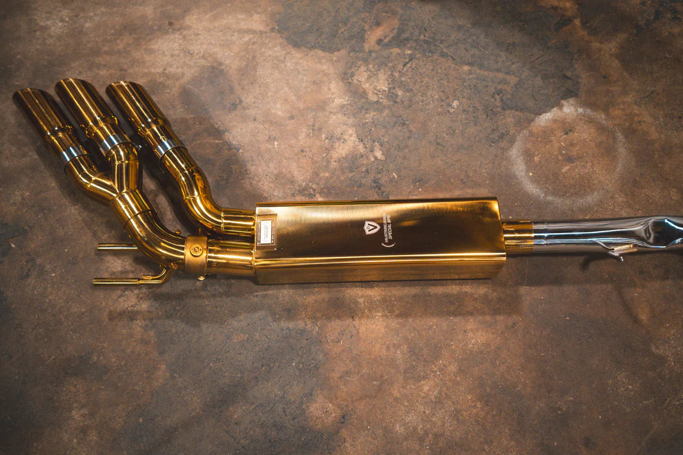 Complete Valvetronic Valved Sport Exhaust System for Mercedes-AMG G63 W463/464 displayed on floor, featuring golden muffler, stainless steel piping, electronic valves, and optional slash-cut tips
