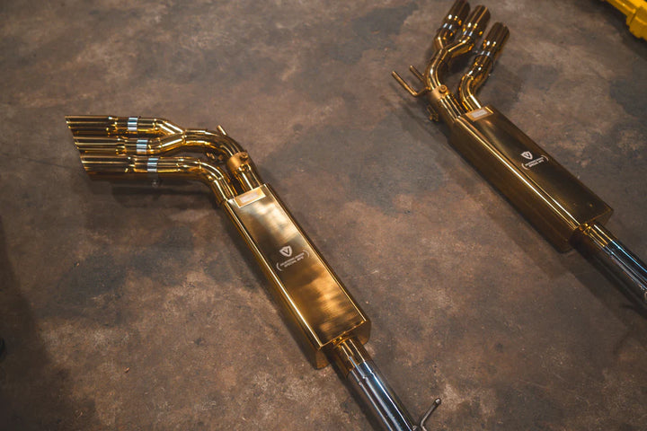 2 Complete Valvetronic Valved Sport Exhaust System for Mercedes-AMG G63 W463/464 displayed on floor, featuring golden muffler, stainless steel piping, electronic valves, and optional slash-cut tips
