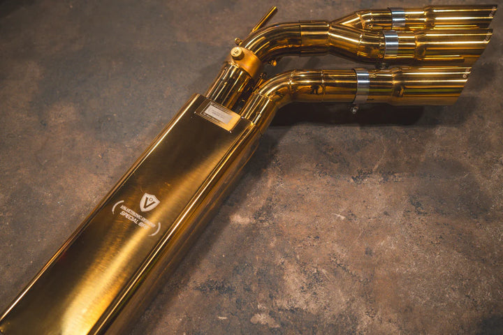 Complete Valvetronic Valved Sport Exhaust System for Mercedes-AMG G63 W463/464 displayed on floor, featuring golden muffler, stainless steel piping, electronic valves, and optional slash-cut tips