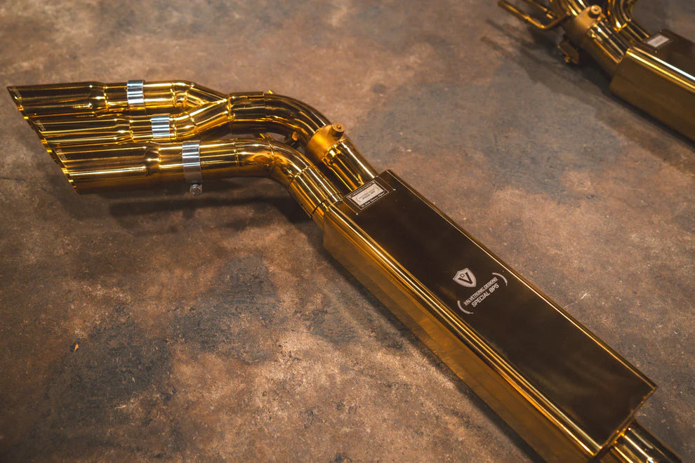 Complete Valvetronic Valved Sport Exhaust System for Mercedes-AMG G63 W463/464 displayed on floor, featuring golden muffler, stainless steel piping, electronic valves, and optional slash-cut tips