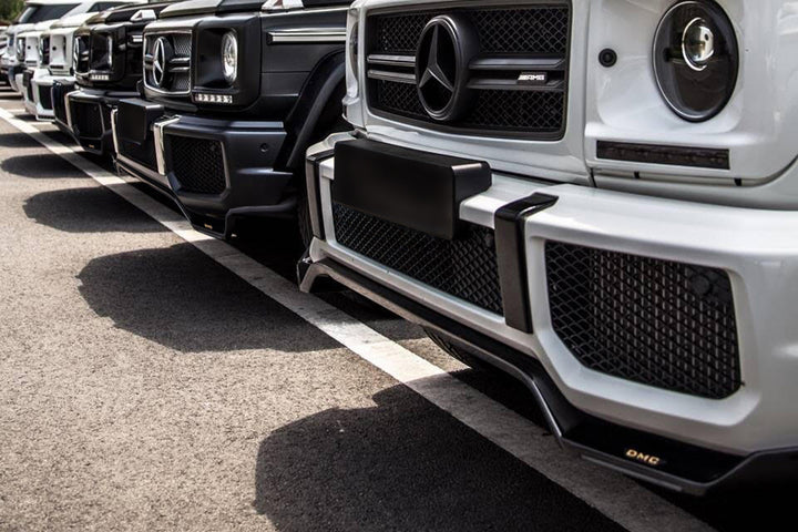 side view of 7 black and white g-wagons parked next to each other with Close-up of DMC Visible Carbon weave pattern on G-Wagon front lip