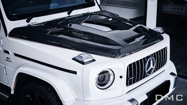 side view of MC forged carbon fiber hood with glass window for Mercedes-AMG G63 (W463A) – marbled weave with gloss finish installed on white AMG G63