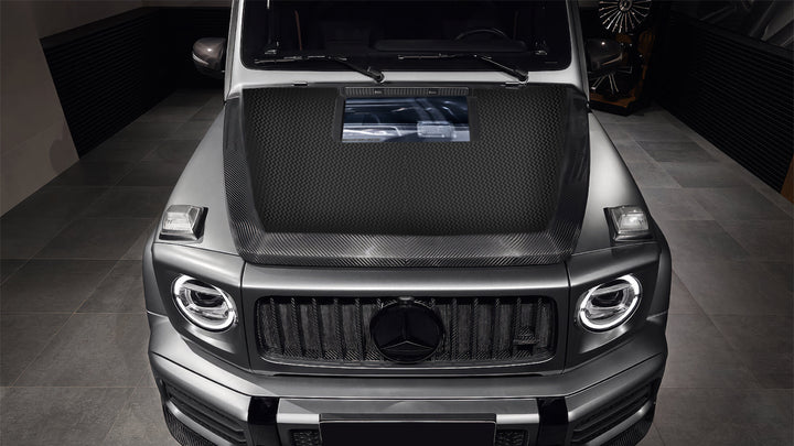 Here’s a refined, SEO-optimized product description with a luxury custom tone, incorporating details from the search results:

DMC Forged Carbon Fiber Hood with Glass Window | 2019+ Mercedes-AMG G63/G500 (W463A/W464)
Where Engineering Meets Exclusivity

Elevate your Mercedes-AMG G-Class beyond factory specifications with the DMC Forged Carbon Fiber Hood, a masterful fusion of avant-garde design and motorsport performance. This OEM-grade replacement transforms your G-Wagon’s front end with a 43% weight reduc