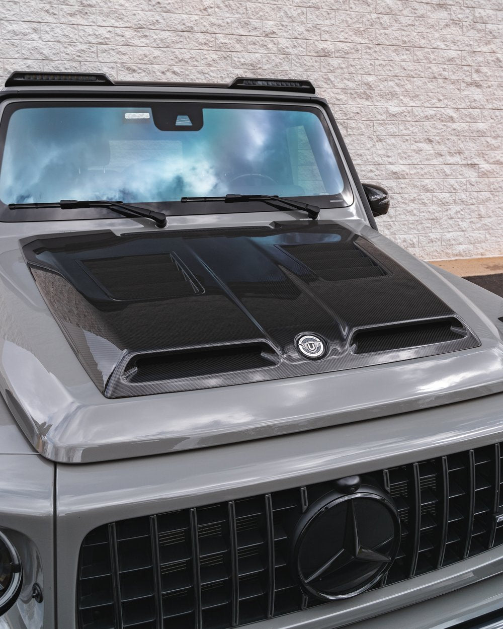 Urban Automotive carbon fiber hood mounted on Mercedes-AMG G63, enhancing performance cooling and aggressive styling.
