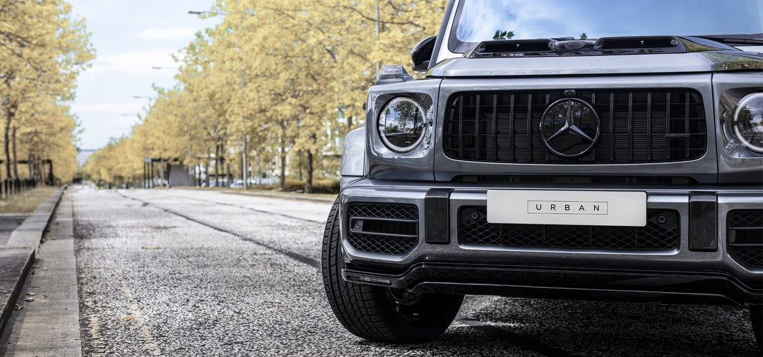 Urban Automotive carbon fiber front splitter mounted on Mercedes-AMG G63 bumper, enhancing aggressive aerodynamic styling.