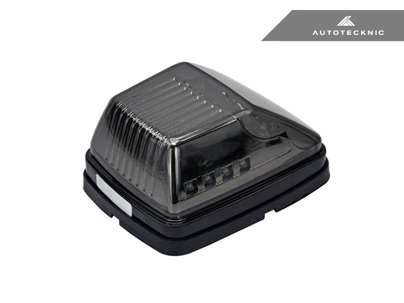 single Close-up of AutoTecknic smoked lens housing for G-Class turn signals - modern blackout finish complements carbon fiber mirror caps on a white background with autotecknic logo on the top right