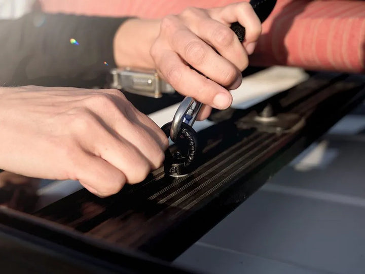 Close-up of galvanized steel Black Tie Down Rings with powder-coated finish, hand-tightened to a roof rack t-slot