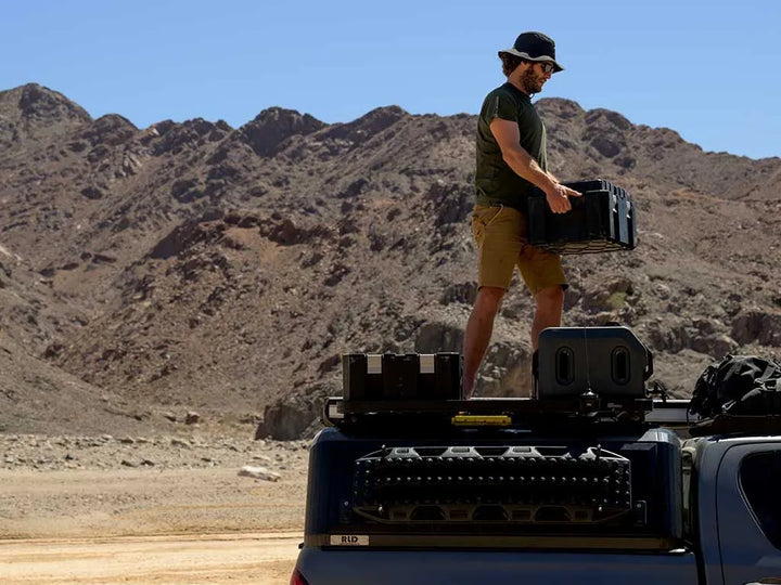 Front Runner Wolf Pack Pro box with Hi-Lid Kit loaded on a vehicle roof rack, demonstrating easy transport and weather protection.
