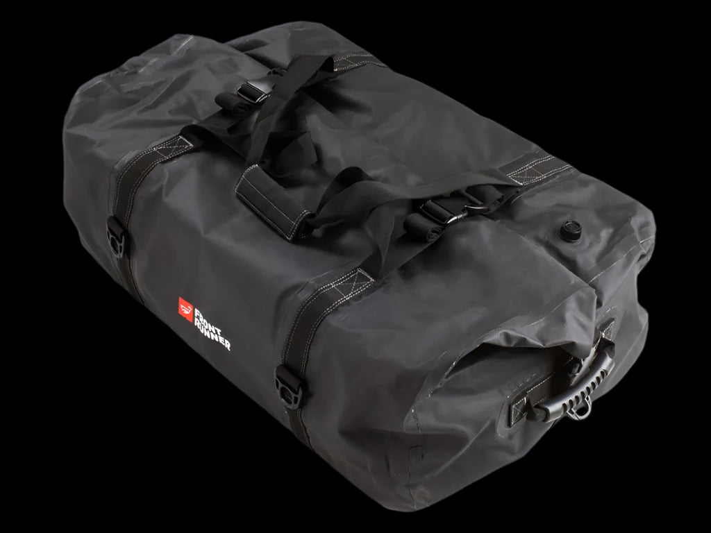 Black Typhoon Bag secured with Stratchits to a vehicle roof rack, keeping camping equipment dry and clean.