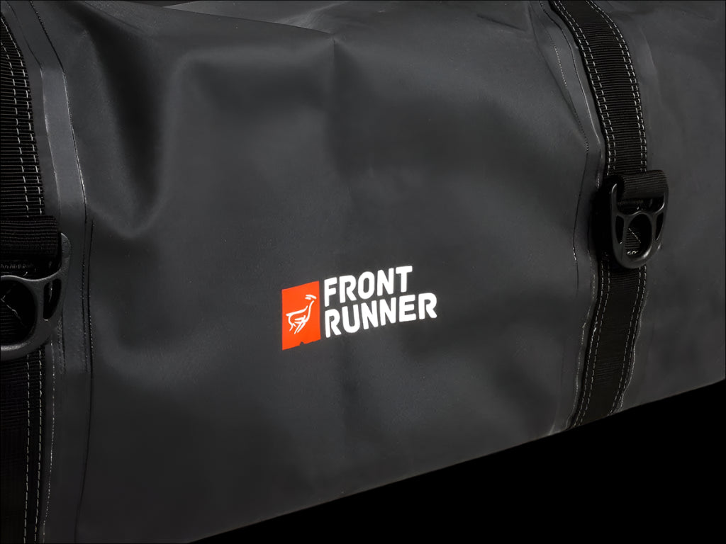 Black Typhoon Bag secured with Stratchits to a vehicle roof rack, keeping camping equipment dry and clean.