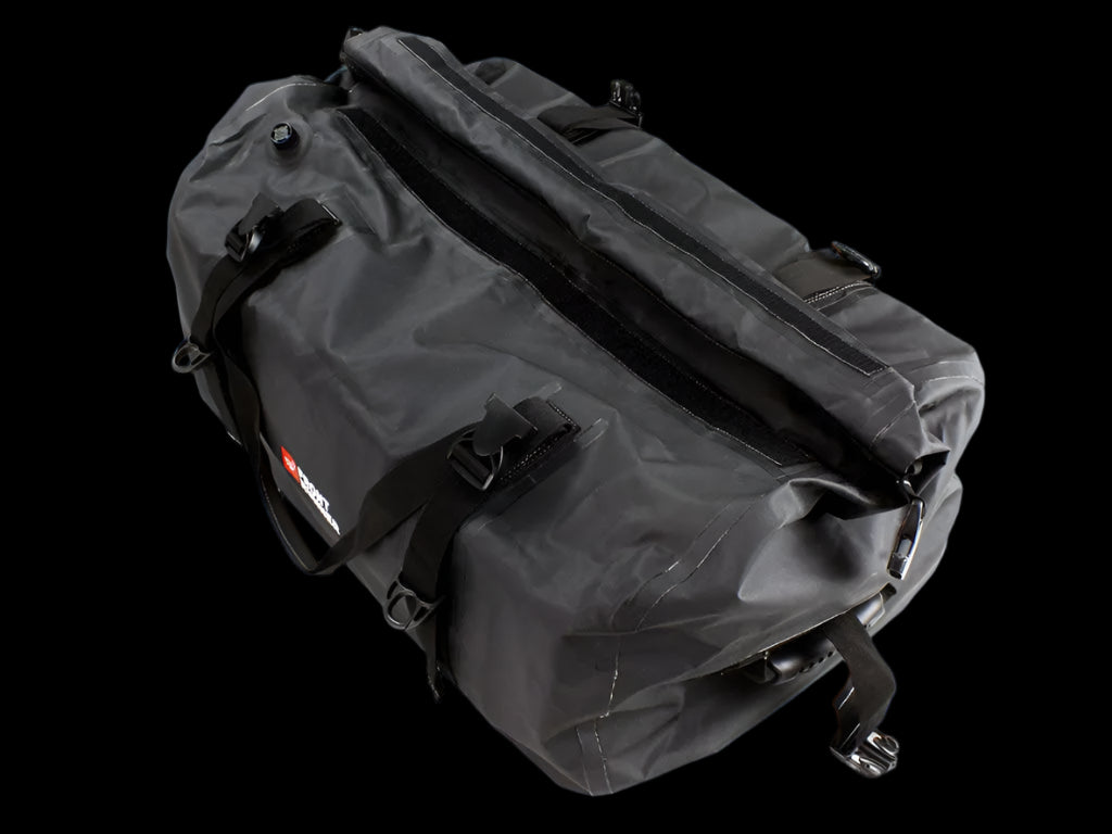 Black Typhoon Bag secured with Stratchits to a vehicle roof rack, keeping camping equipment dry and clean.