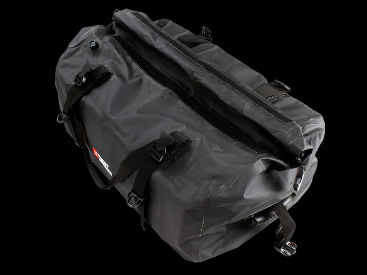 Black Typhoon Bag secured with Stratchits to a vehicle roof rack, keeping camping equipment dry and clean.