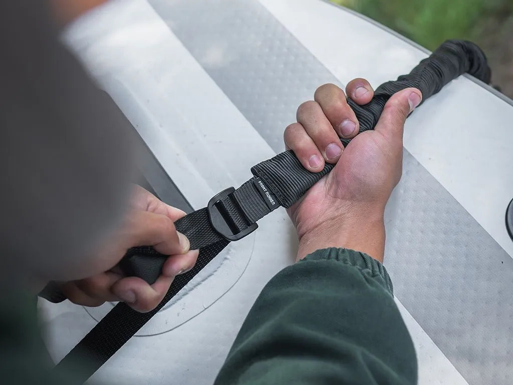 Stratchits hooked to Front Runner roof rack tie down rings, securing firewood and bicycles for a rugged overlanding adventure