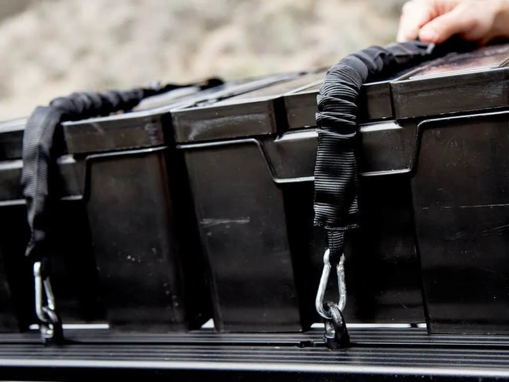 Front Runner Stratchits securing a Wolf Pack Pro storage box to a roof rack with stainless steel carabiners and Velcro strap discipline
